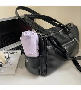 Détail de la poche latérale sur le sac messager noir contenant un parapluie violet
