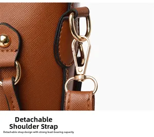 Close-up of golden metal swivel hook and textured leather strap on brown tote bag