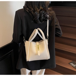 Detailed view of beige lychee leather bag with golden metal twist lock on stairs