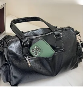 Détail de la poche zippée avant d'un sac en cuir noir avec téléphone à l'intérieur