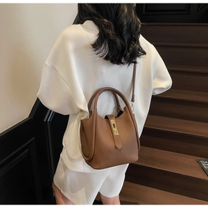 Détail d'un sac seau en cuir marron grainé avec fermoir doré et poignée élégante