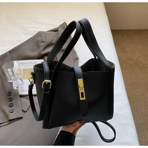 Close-up of black litchi pattern leather bucket bag with elegant gold twist lock detail
