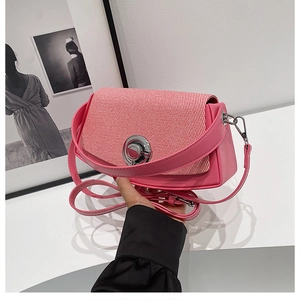Detailed shot of pink PU leather bag with textured red and white woven patchwork and metal lock