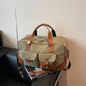 Large military green canvas travel bag with leather accents on a leather chair background