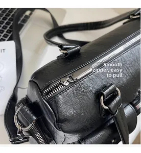 Détail de la fermeture éclair argentée fluide sur un sac Boston en cuir noir