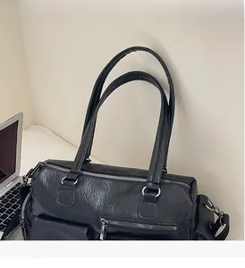 Détail du sac messager noir grainé avec plusieurs poches zippées et des doubles poignées