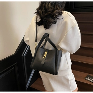 Close-up of black litchi grain leather bucket bag with gold metal buckle detail