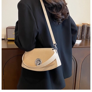 Detail of beige corduroy crossbody box bag with large silver round clasp on black blazer