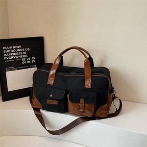 Black canvas travel bag with brown leather trim and adjustable shoulder strap