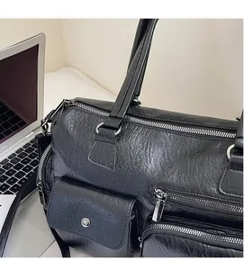 Gros plan du sac cabas en cuir souple noir avec plusieurs poches et fermetures éclair argent