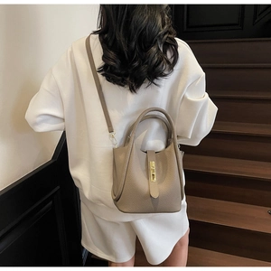 Vue détaillée du sac seau taupe en cuir avec poignée et fermoir cadenas doré