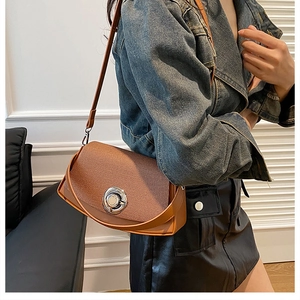 Detail of tan textured PU leather crossbody bag with large silver circular twist lock
