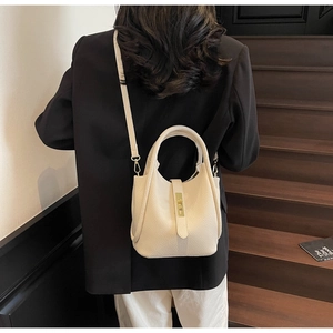 Détail du sac seau blanc cassé avec texture litchi, boucle dorée et bandoulière