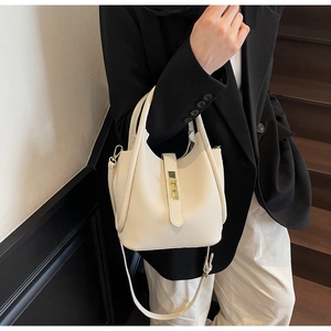 Détail du sac seau blanc crème avec motif litchi, fermoir doré et bandoulière réglable