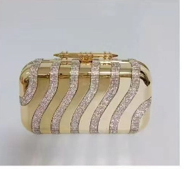 Macro shot of wavy gold evening clutch featuring shimmering rhinestone stripes and metal clasp