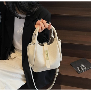 Détail du sac seau en cuir grainé blanc cassé avec boucle dorée et finition texturée