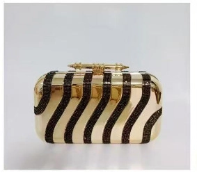 Macro detail of luxury gold acrylic clutch with shimmering black rhinestone zebra stripes