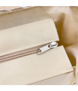 Detailed macro shot of the smooth silver zipper closure on beige canvas beach bag