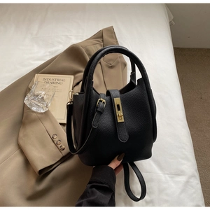 Détail du sac seau noir en cuir à motif litchi avec fermoir rotatif doré élégant