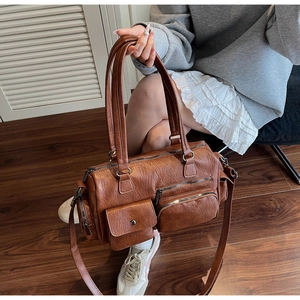 Détail d'un sac vintage marron avec texture litchi et plusieurs poches zippées pratiques