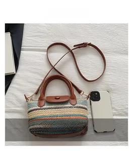 Detail view of woven straw mini bag with brown leather strap and fold-over flap cover