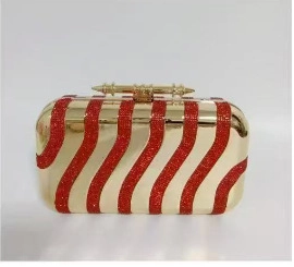 Detail of gold acrylic evening clutch with red wavy sequin stripes and metal clasp