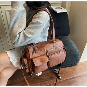 Sac bandoulière vintage marron avec design multi-poches porté par un mannequin chic