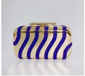 Detail of evening clutch featuring blue crystals and golden wave patterns with spike clasp