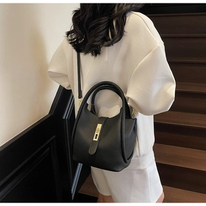 Détail d'un sac à main en cuir noir grainé avec fermoir doré et bandoulière