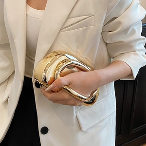 Detail of glossy gold metallic evening clutch with modern ergonomic ring handle