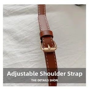 Close-up of adjustable brown leather shoulder strap with a polished gold buckle