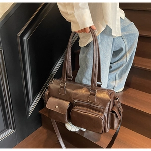 Gros plan d'un sac besace vintage en similicuir marron foncé avec plusieurs poches pratiques