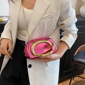 Détail d'un mini sac rose métallisé avec poignée en C dorée porté sur un tailleur blanc