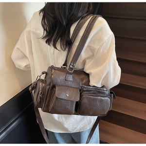 Vue détaillée du sac vintage marron foncé avec design multi-poches sur texture en cuir