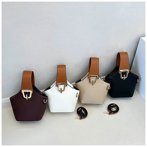 Detail view of four minimalist bucket bags with wide brown handles and horseshoe buckles