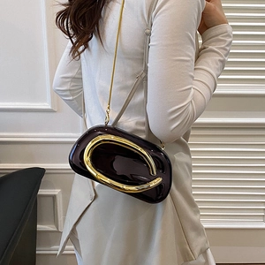 Close-up of a glossy clutch with a large gold circular buckle and chain strap