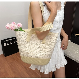 Close-up of white floral lace pattern and beige woven straw base on beach tote bag
