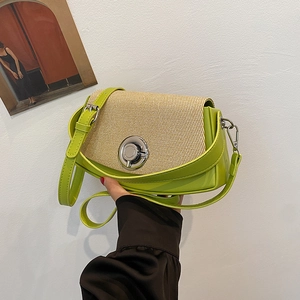 Green PU leather and woven crossbody bag with a round silver lock held in a hand