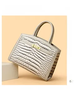 Detail shot of beige faux crocodile leather texture and golden metal lock on handbag