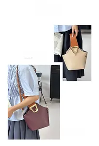 Detail of minimalist bucket bag with contrast handle and golden trapezoid clasp