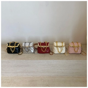 Quilted mini crossbody bags in five colors with metal chain handles on stone steps