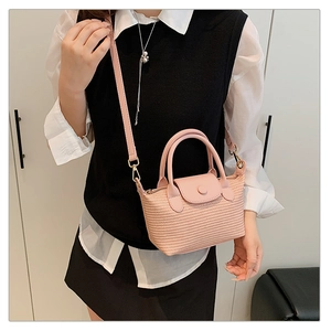 Detail of pink woven basket bag with leather handle and strap on model in white shirt
