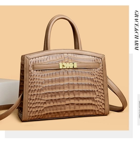 Detail of brown crocodile pattern handbag with gold metal lock and leather strap