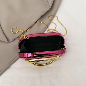 Detail view of pink evening clutch with gold metal handle and black fabric lining inside