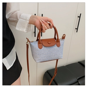 Detail of blue and white woven texture with brown leather handle and gold hardware