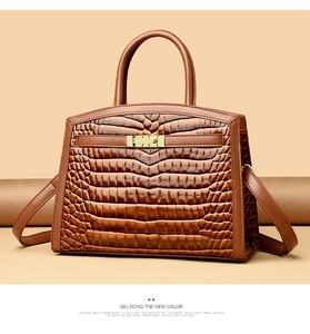 Detail of caramel brown crocodile embossed handbag with luxury gold turn-lock closure