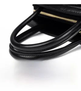 Detail of reinforced handles and precision stitching on a black leather handbag