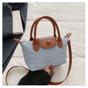 Close-up of blue and white woven texture with brown leather handle and gold hardware