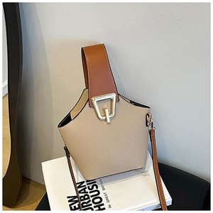 Detail of a minimalist two-tone bucket bag with beige leather and gold buckle clasp