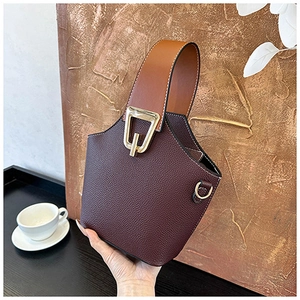 Detail of burgundy grained leather bucket bag with contrasting brown handle and gold buckle